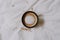 Black and white cup of coffee between bed sheets decorated with some dried flowers. Relaxing photo. Morning coffee concept