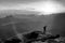 Black and white dashed retro sketch. Man stands on the peak of rock watch to Sun. Beautiful moment the miracle of nature