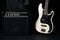 Black and white electric bass guitar with amplifier, jack cable,