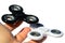 Black and white fidget spinners balancing on tips of fingers of adult male person, white background