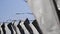 Black and white flags with tapes sway on wind in summer day. Blue clear sky. Column with flag