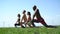 Black and white guys and two girls warm up on a green meadow