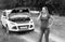 Black and white image of angry young woman talking to car service beacuse of her broken car