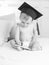 Black and white image baby in graduation hat using tablet