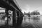 Black and white image concept of concrete bridge crossing the river with background group of boats