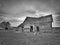 Black and white image of dreary abandoned dilapidated farm house in northern Minnesota