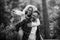 Black and white image with happy and joyful adult caucasian couple having fun in outdoor forest leisure activity - man carry woman