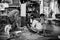 A black and white image with an indian boy playing around his dad while father is working