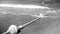 Black and white image of life saving buoy line on the rope lying on the sandy sea beach and flotaing on water surface