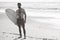 Black and white image of male surfer on the beach