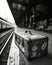 Black and white image of an old suitcase in a train station.