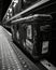 Black and white image of an old suitcase in a train station.