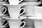 Black and white image of the white cups and saucers arranged in the rows.