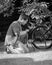 Black and white image of young man pumping bicycle wheel with air