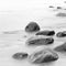 Black and white impression of the evening sea shore with water and stones on a beach