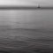 Black and white impression of a lonely sailboat sailing on an endless sea