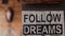 Black and white inscription Follow Dreams on wooden column in the room