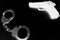 Black and white negative photo of crime symbols handcuffs and gun