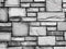 Black and white, old rough textured paved brick wall.