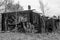 Black and white photo of the abandoned remains of a burnt down wooden building