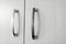 Black and white photo, close-up detail of metal knobs, of pastel beige cupboard, in the kitchen area.