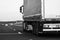 Black and white photo, concept of motion, loaded European truck in motion on asphalt road, transportation and delivery concept.