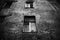 The black-white photo depicts an old, grey, and somber building with dark windows. Sadness and nostalgia, decay. The emptiness of