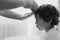 Black and white photo. Father cuts her son hair in the room. Family during quarantine, Scissors and a comb in male hands