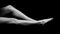 Black and white photo of female legs lying on black void and pulling toes, side view isolated on black background