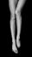Black and white photo of female legs lying on black void and pulling toes, top view isolated on black background