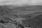 A black and white photo of a road leading far away through a dry mountanous landscape in the sierra