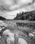 a black and white photo of rocks and a stream that runs between the trees