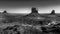 Black and White Photo showing the gravel road winding around East and West Mitten Buttes in desert landscape in Monument Valley