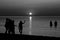 Black and white photo of silhouettes of teenagers playing in the sea during sunset