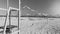 Black and white photo of vollyeball net on the beach fluttering under heavy strong wind at bright sunny day