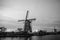 Black-white photo of windmills and water canal on sunset in Kinderdijk, Holland
