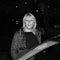 black and white photo of woman waiting behind a car.