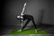 Black white photo of Young beautiful woman brunette in black clothes practice yoga utthita trikonasana in dark studio green mat