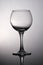 Black and white photograph is an empty glass for wine on a gray gradient background.