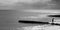 Black and white photograph of a six year old unrecognisable boy walking along a jetty in the sea