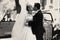 Black and white photograph of a wedding couple kissing behind a