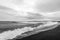 Black and white photography of waves crash ashore on Hvalnes beach in Hvalnes peninsula in Iceland.