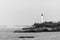 Black and white picture of Biarritz lighthouse on rocks, blurry horizon. Pyrenees-Atlantiques department, French Basque Country