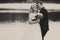 A black and white picture of a happy wedding couple standing behind a lake