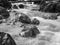 Black and white picture of a mountain stream or creek flowing between rocks. Seven ladders canyon in Piatra Mare Big Rock