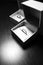 Black and white picture of two wedding rings in ring boxes on black background