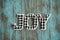 Black and white plaid Joy word letters on a teal wood background, useful for rustic Christmas holiday projects