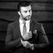 Black-white portrait of beautiful fashionable man in stylish suit against wooden background