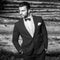 Black-white portrait of beautiful fashionable man in stylish suit against wooden background