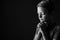 Black and white portrait of praying boy on dark background